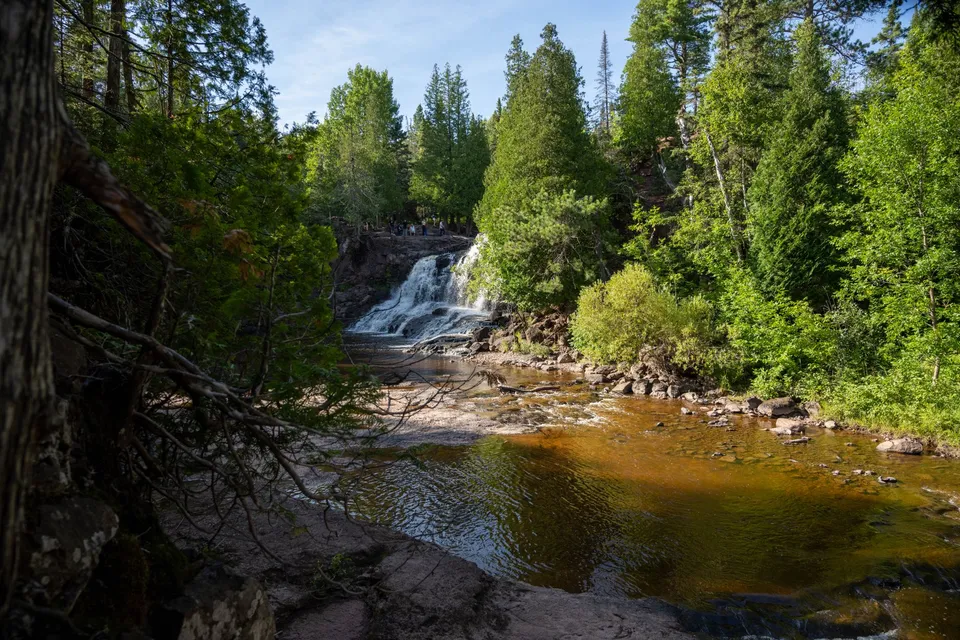 Tranquil view of a waterfall surrounded by lush green forest in Duluth, Minnesota.