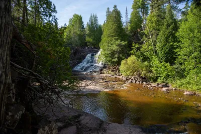 Tranquil view of a waterfall surrounded by lush green forest in Duluth, Minnesota.